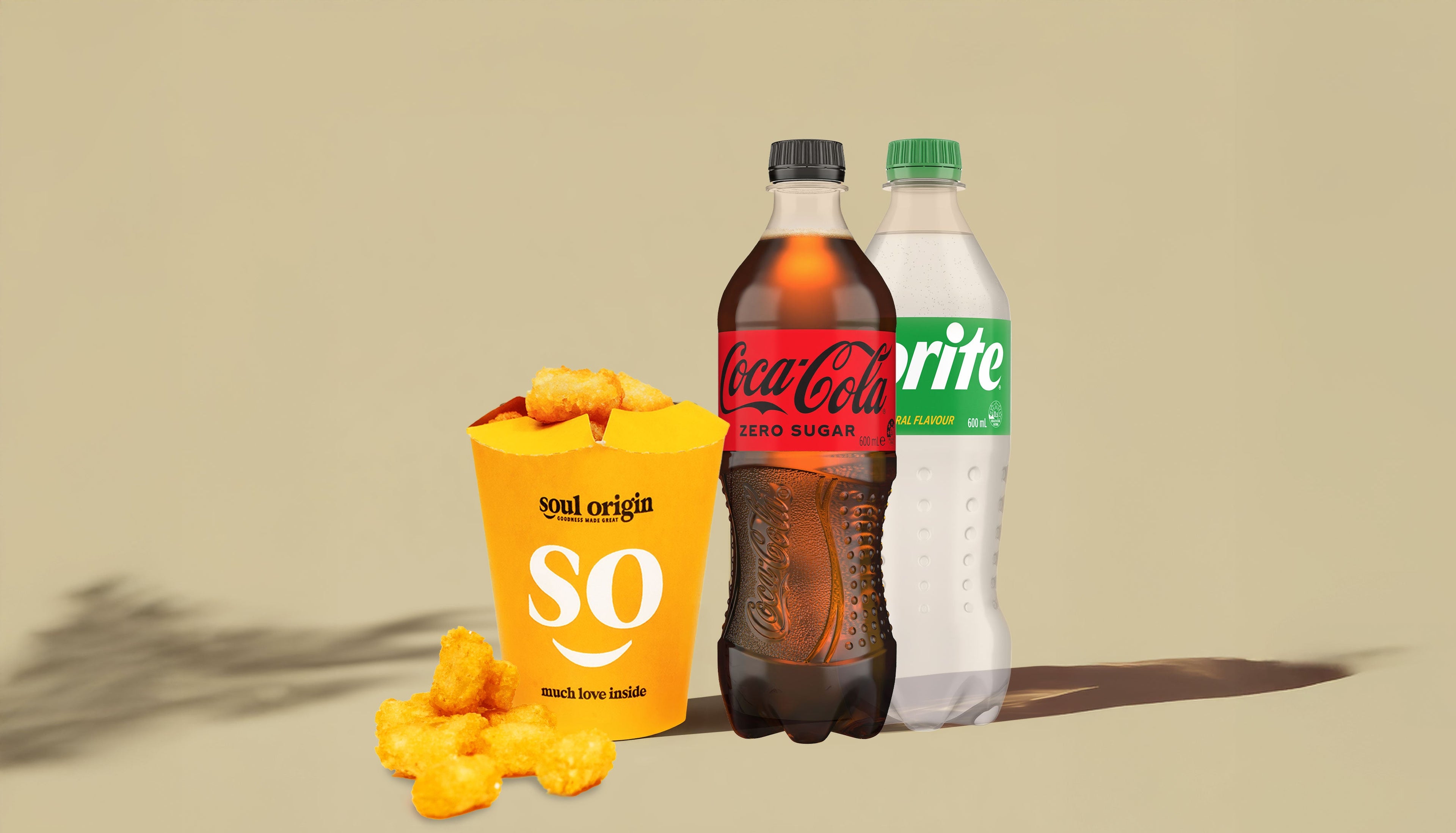 Coca-Cola and Sprite bottles with a yellow bag labeled 'soul origins' on a beige background