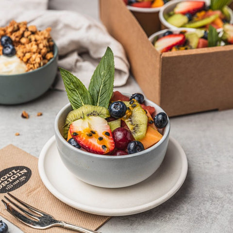 Bowl of fruit with granola in the background