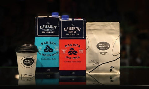 Left to right: a coffee cup, two cartons of almond and oat milk, bag of espresso roast