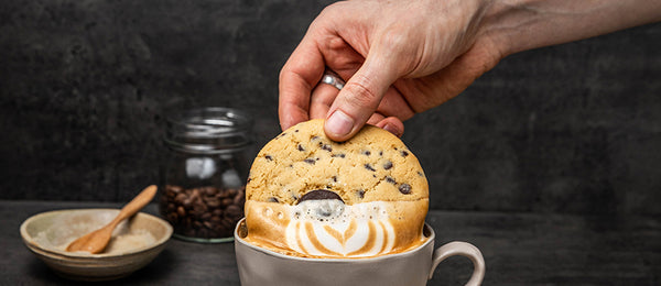Hand dipping a cookie into a cup of coffee